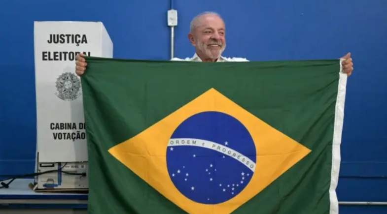 Lula ergue bandeira do Brasil em seção eleitoral | Reprodução/ Nelson Almeida/AFP